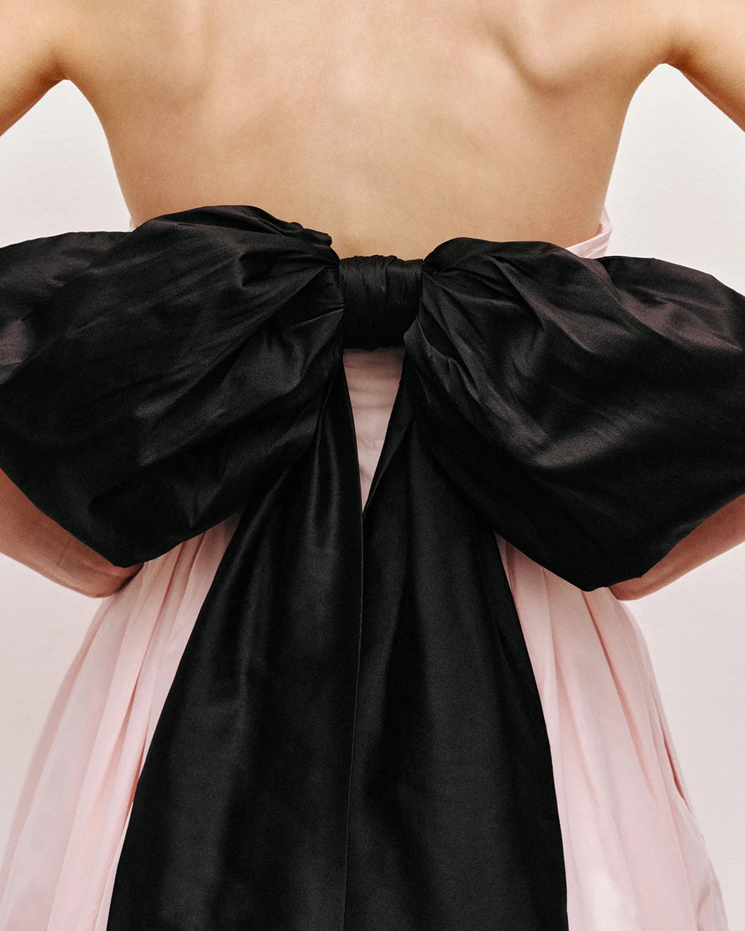 Thea strapless pink tint gown with large black bow at the back by aje shown from the back detail view