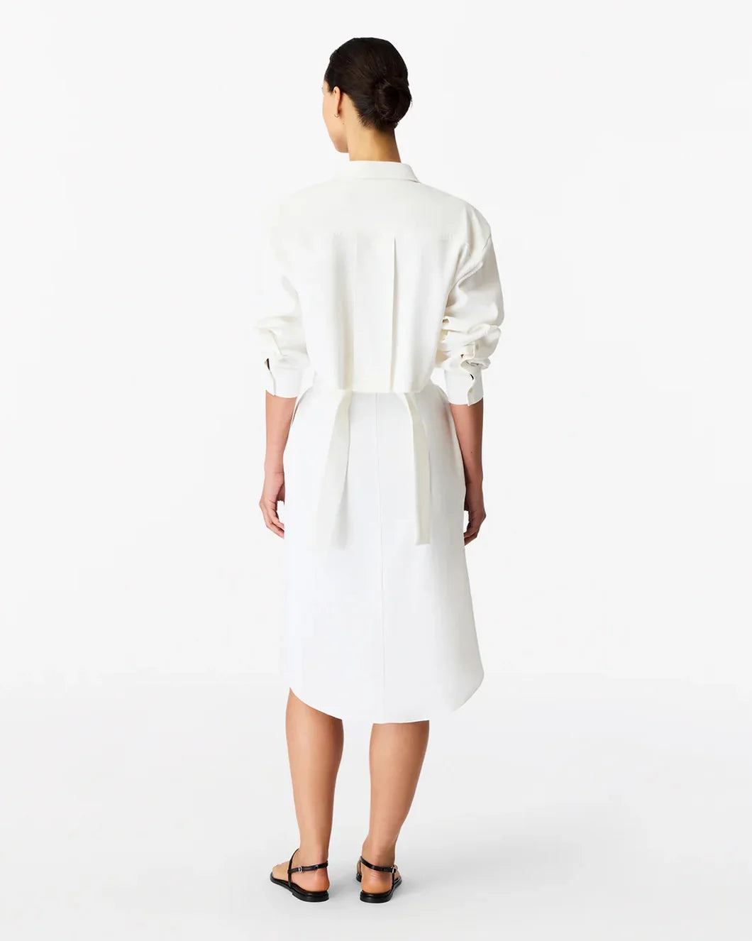 Woman wearing a white dress back view on a plain background