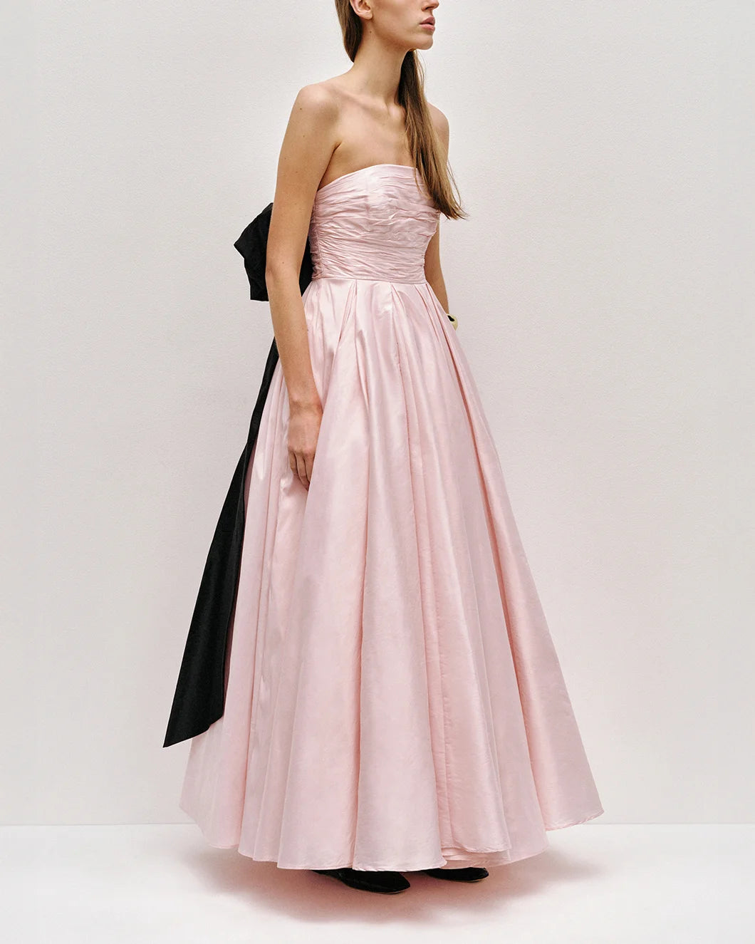Thea strapless pink tint gown with large black bow at the back  by aje shown from the side view