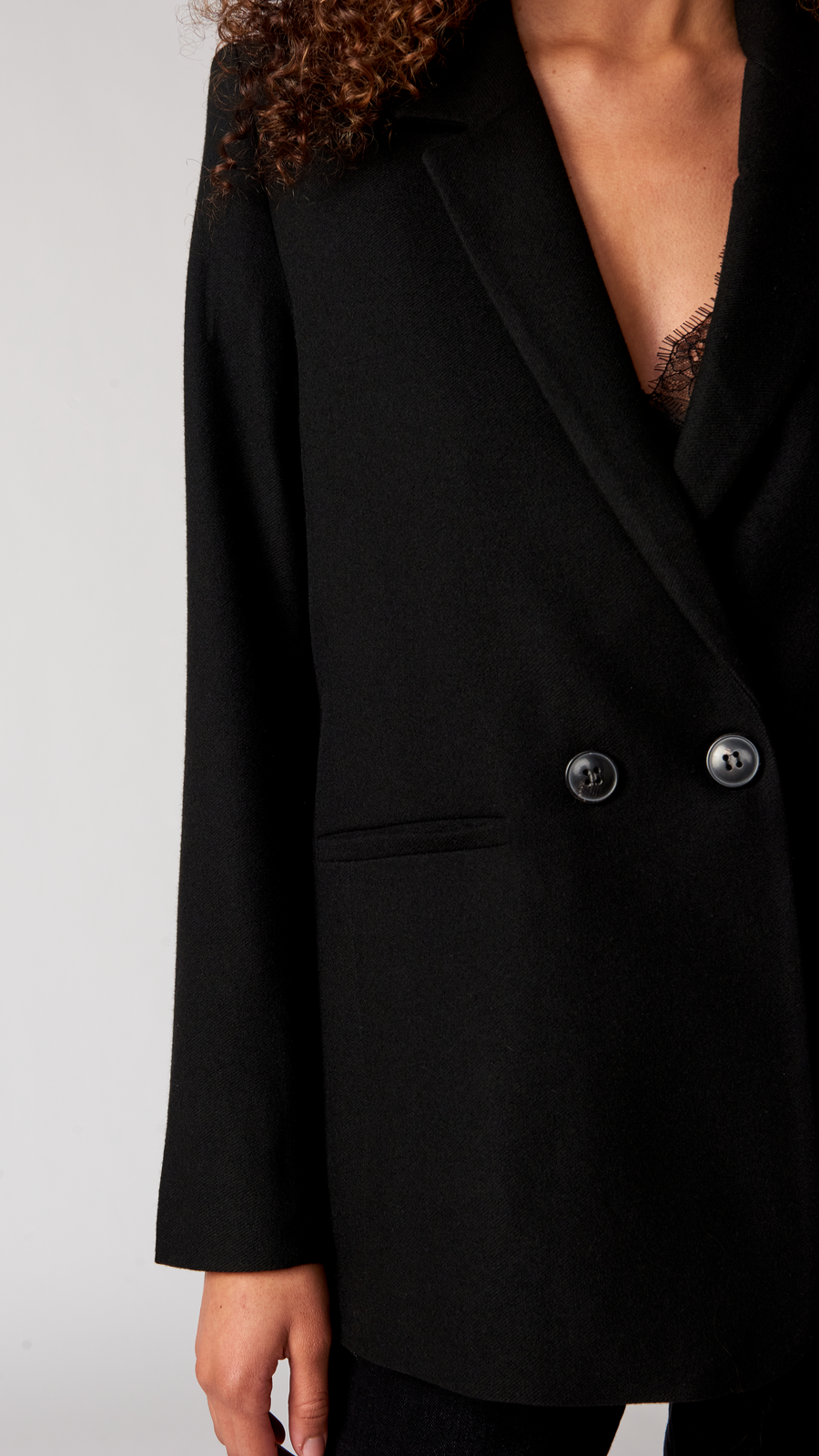 A close up detail of a black blazer with two buttons on it.