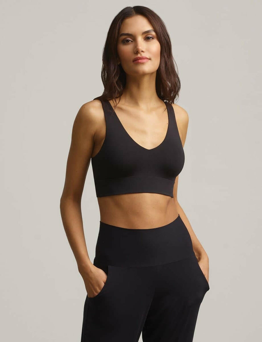 A woman wearing the black butter comfy bralette paired with black pants.